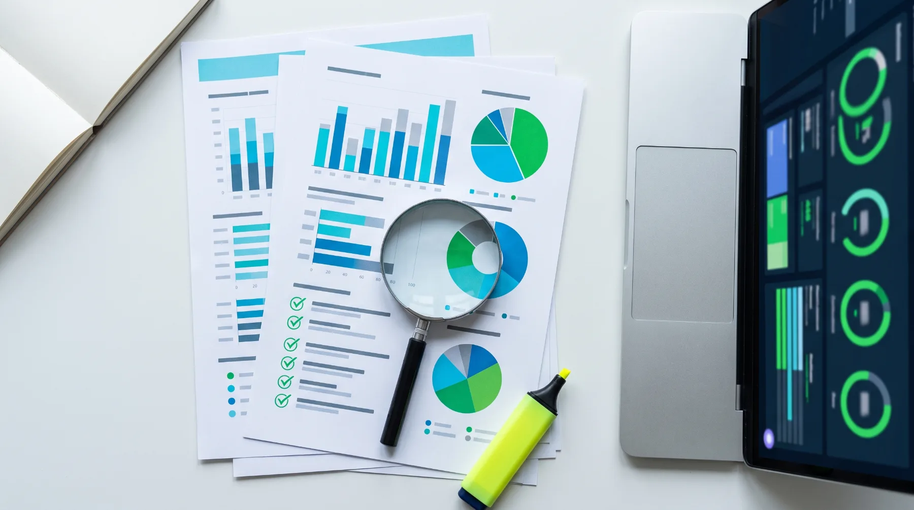 A magnifying glass on printed website audit reports beside a laptop showing performance gauges